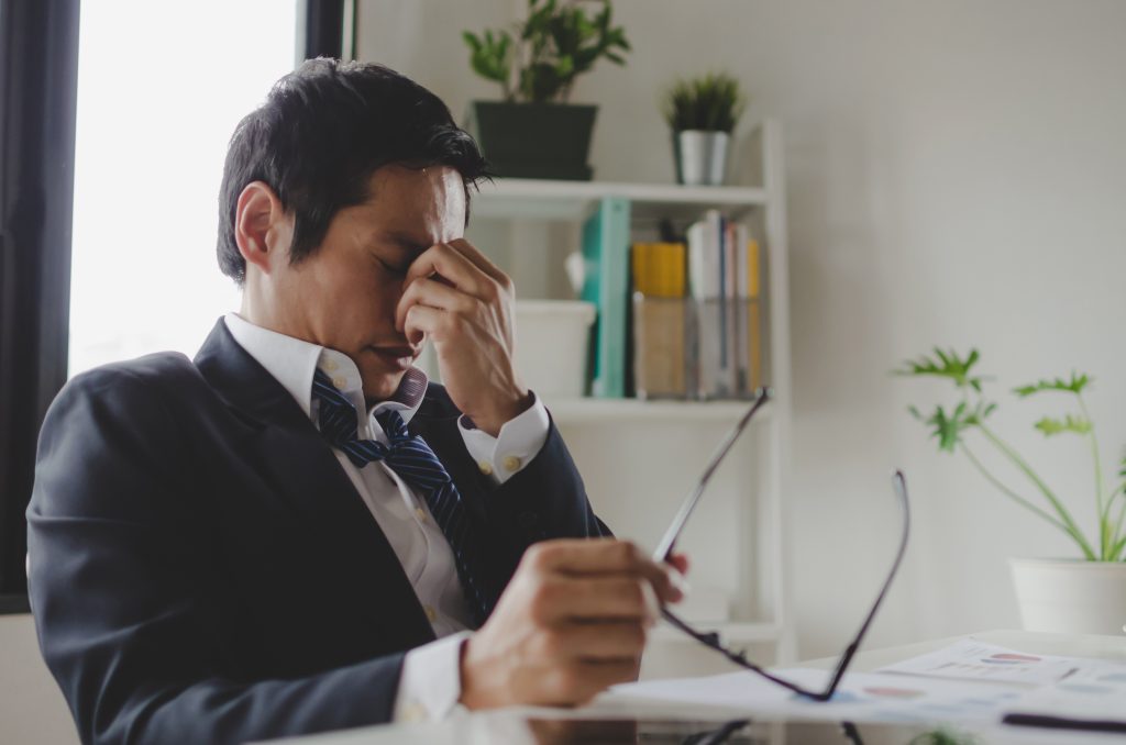 jeune homme d'affaires fatigué se sentant stressé et enlevant ses lunettes ressent une fatigue oculaire.
