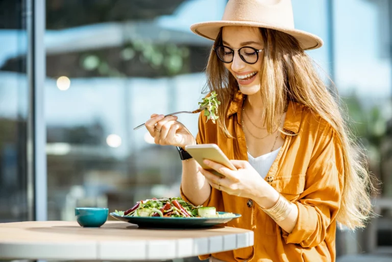 femme qui mange en regardant son téléphone